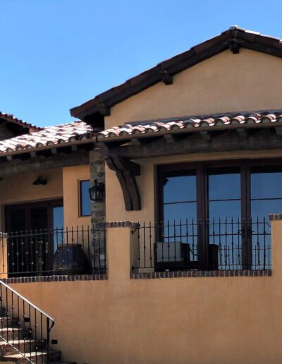 A tan house with stairs and a balcony.