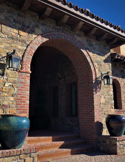 A stone house with a stone archway and two urns.